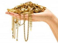 hand holding pile of gold chains