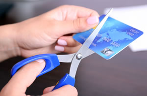 woman cutting a credit card with a pair of scissors