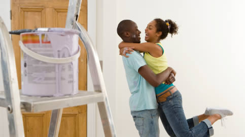 couple happy they have decorated a room, with a ladder and a paint pot