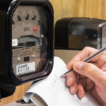 Man reading the lectric meter and writing it down